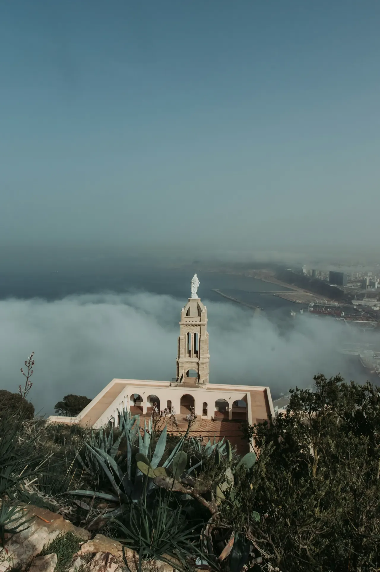 a white building with a tower and a foggy city in the background