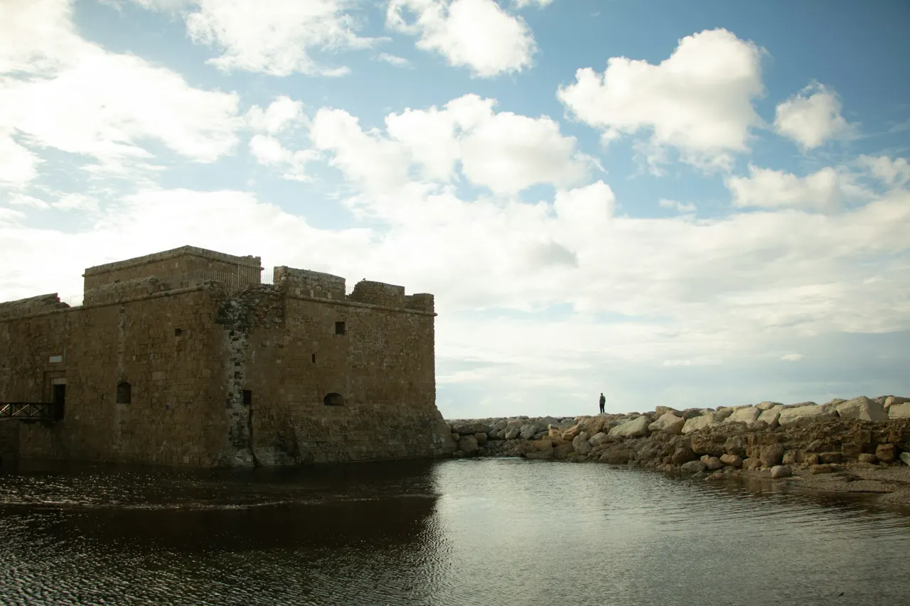 a man standing on a stone wall next to a body of water