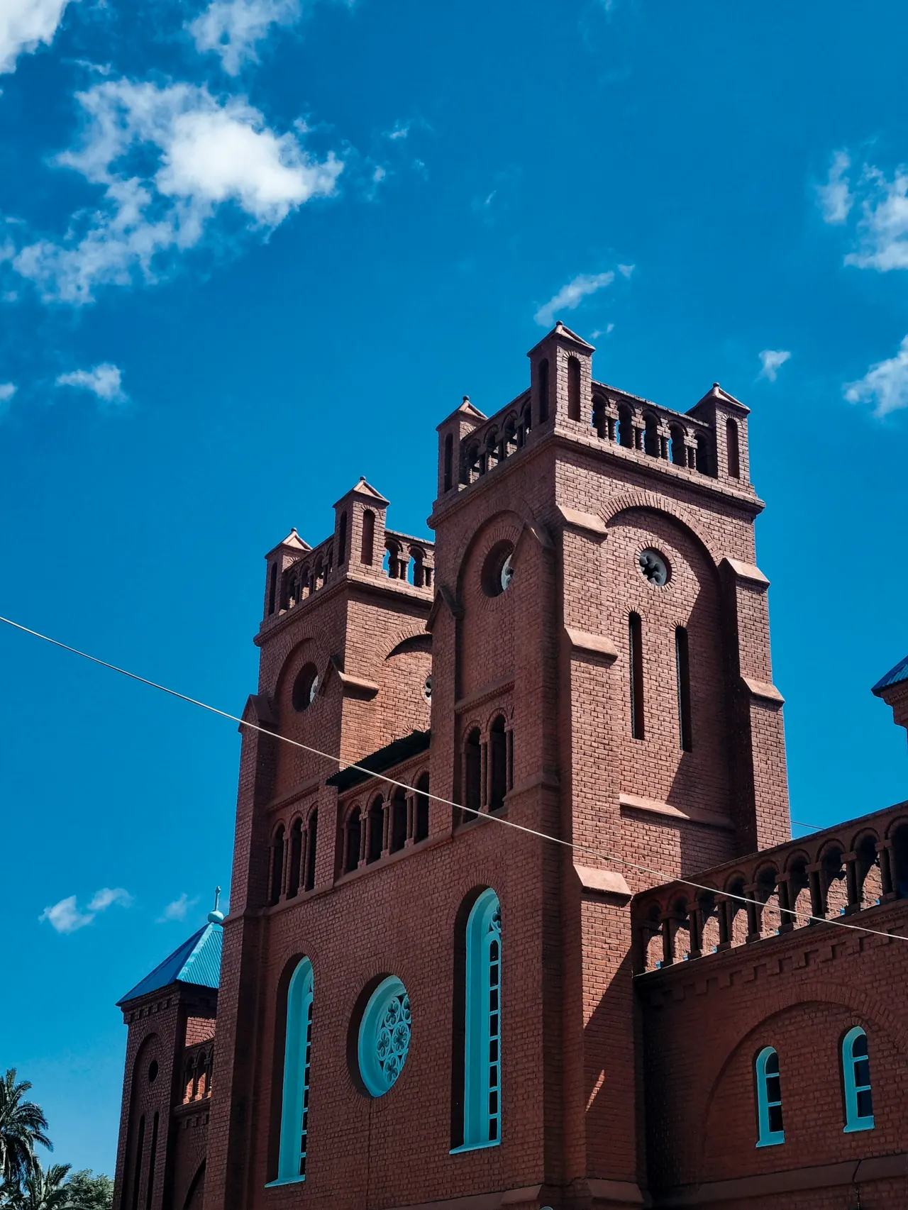 A brick church stands against a blue sky