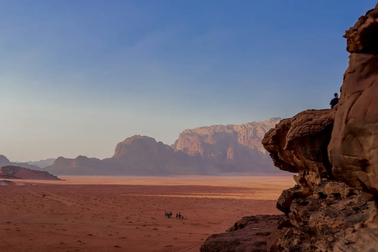 a group of people riding horses through a desert