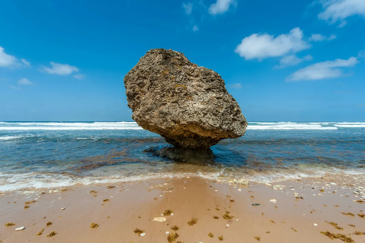 a rock sticking out of the water on a beach