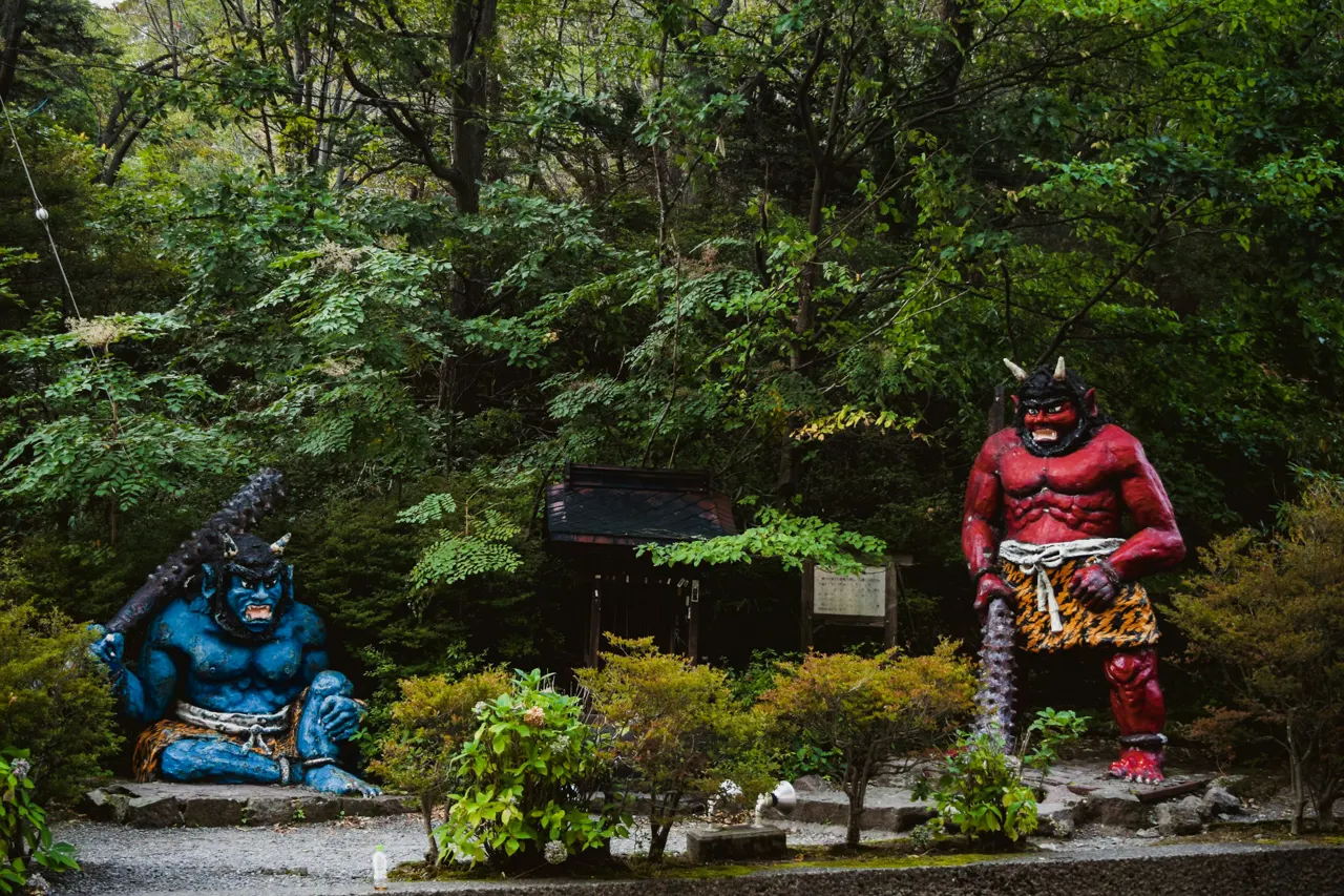 a couple of statues sitting in the middle of a forest