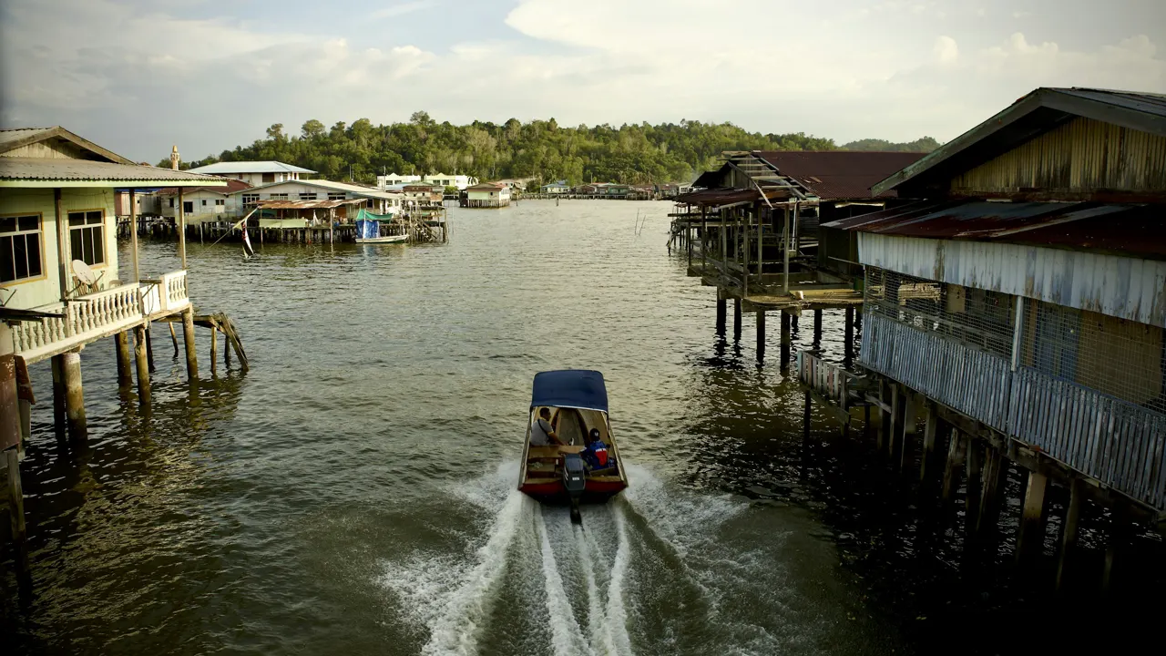 a boat traveling down a river next to a wooden pier
