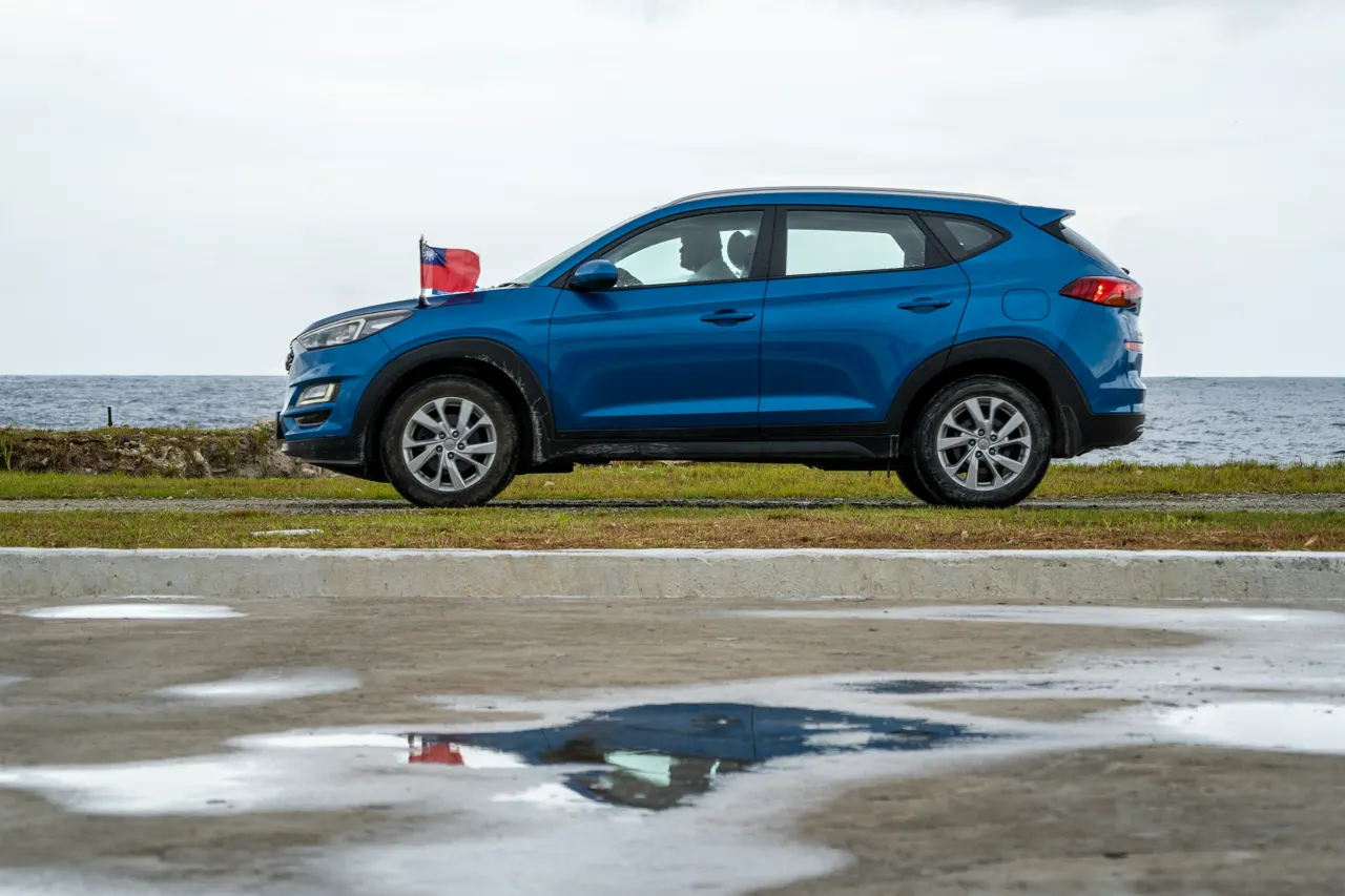 A blue car parked next to a body of water