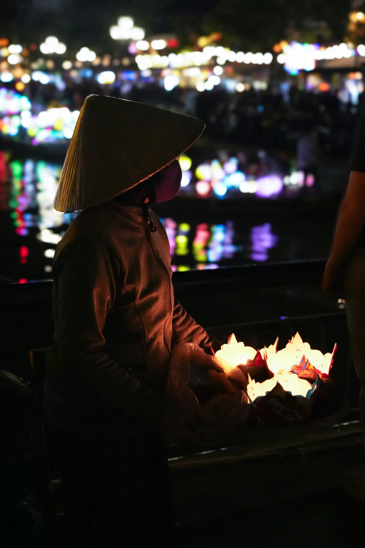 A woman sells floating candles at night