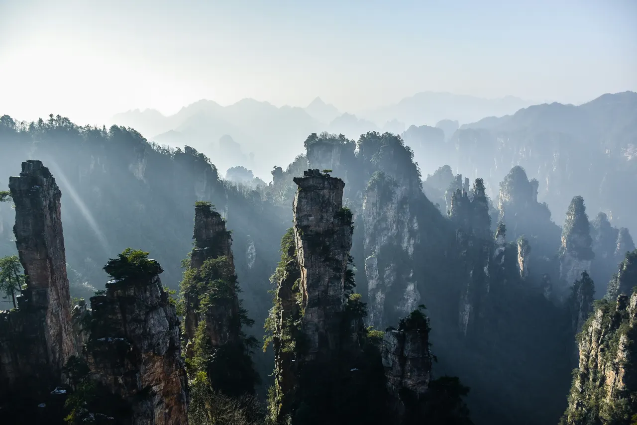 Tall sandstone pillars rising above a misty valley in Zhangjiajie National Forest Park