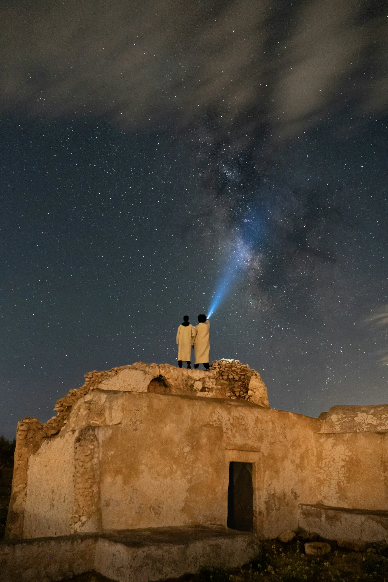 Night sky meets history at Sidi Aich Mosque in Jaabira, Djerba, as the Milky Way is illuminated by a beam of light