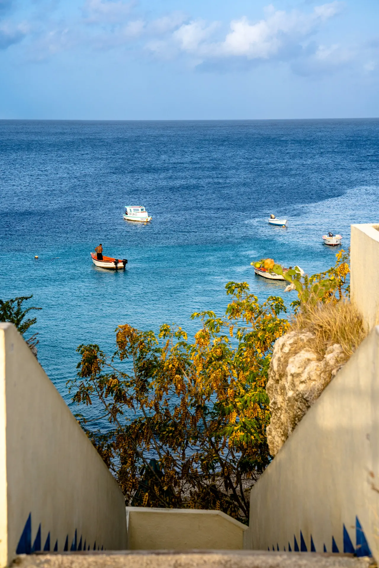 A fisherman and several small fishing boats off the coast of the Caribbean island of Curaçao