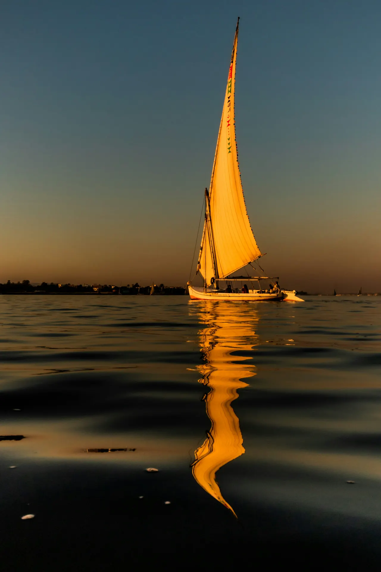 A felucca sail boat on the River Nile reflected in the water