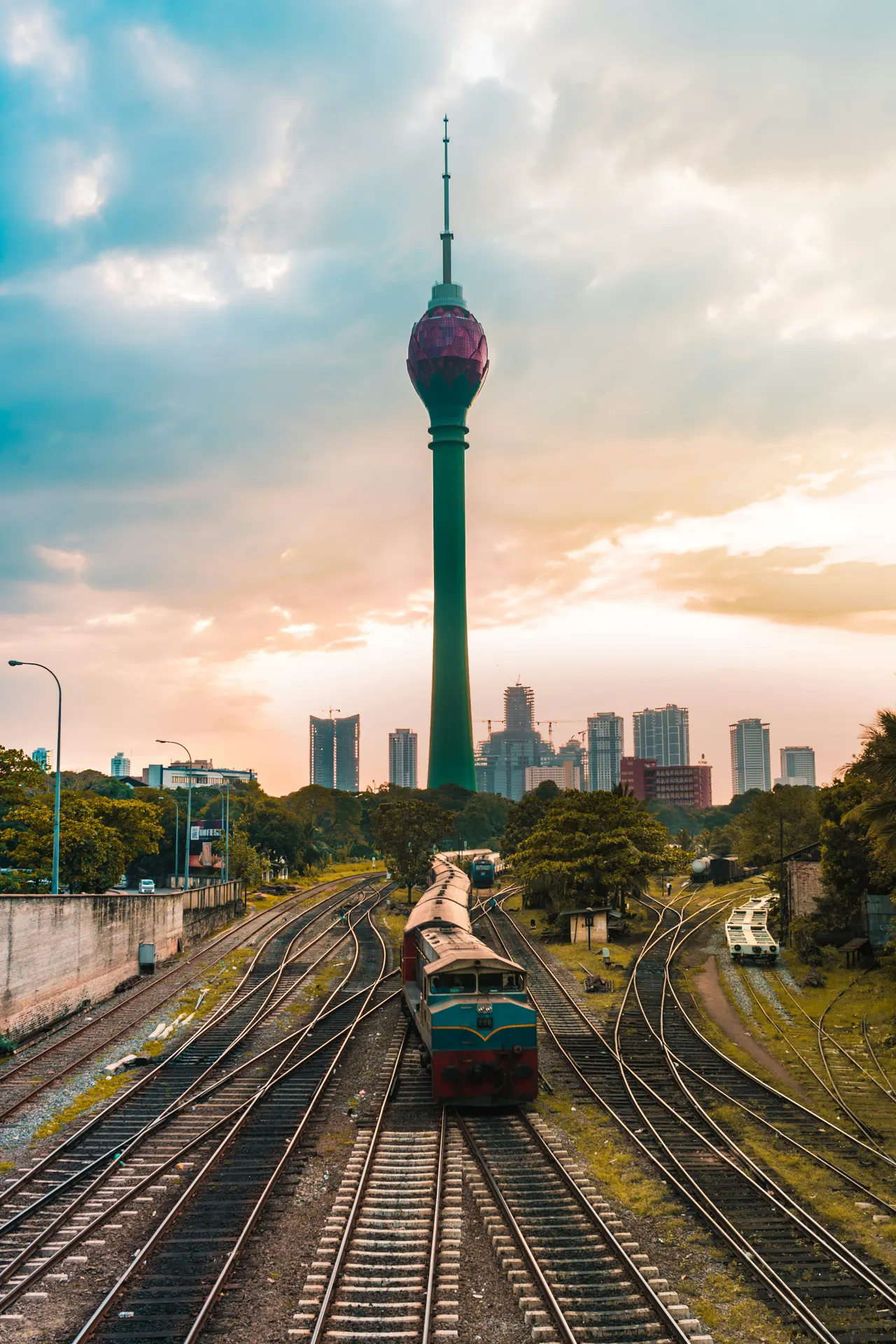 A train on tracks leading toward the Lotus Tower in Colombo at golden hour