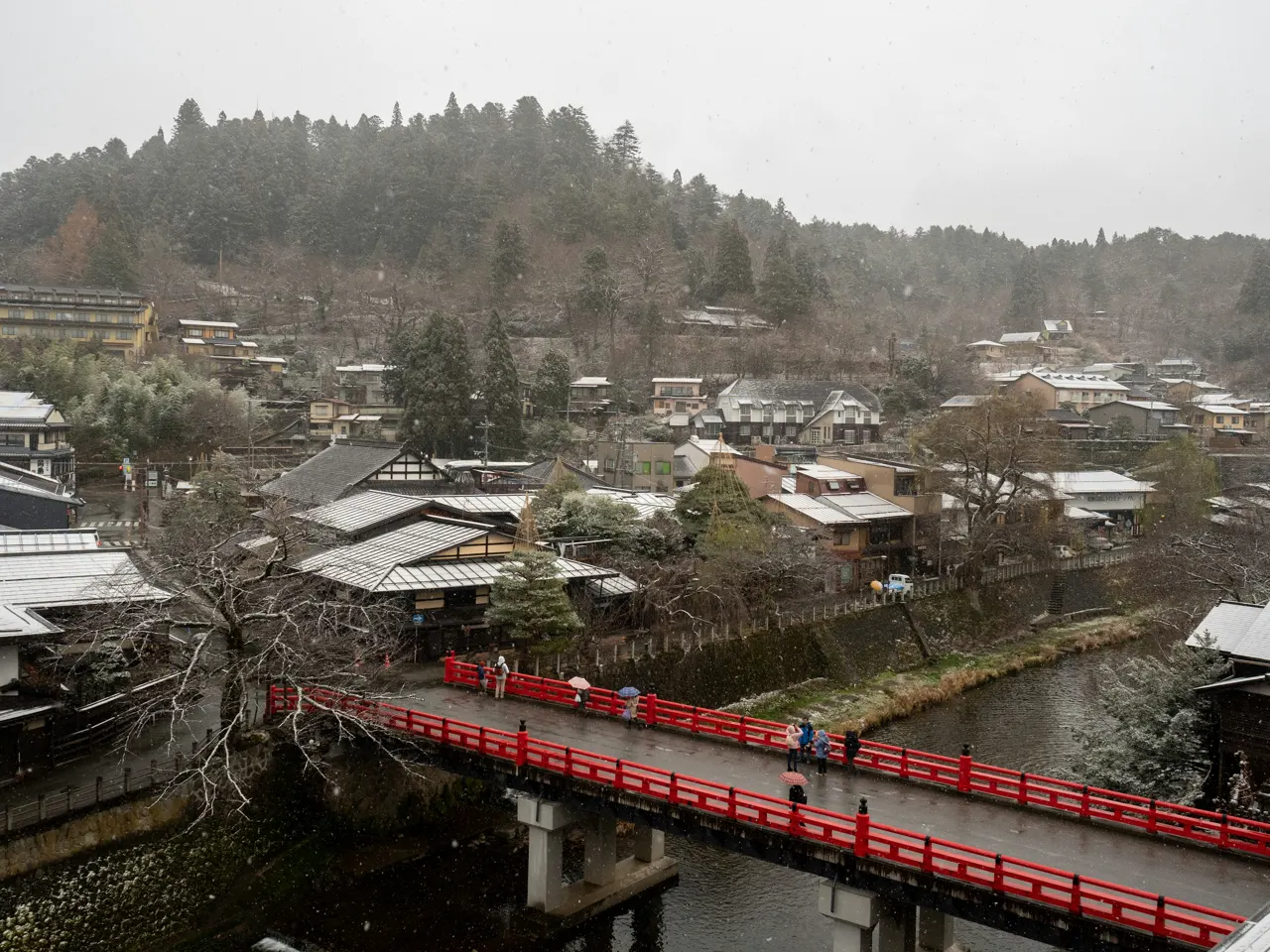 a red bridge over a river in a small town
