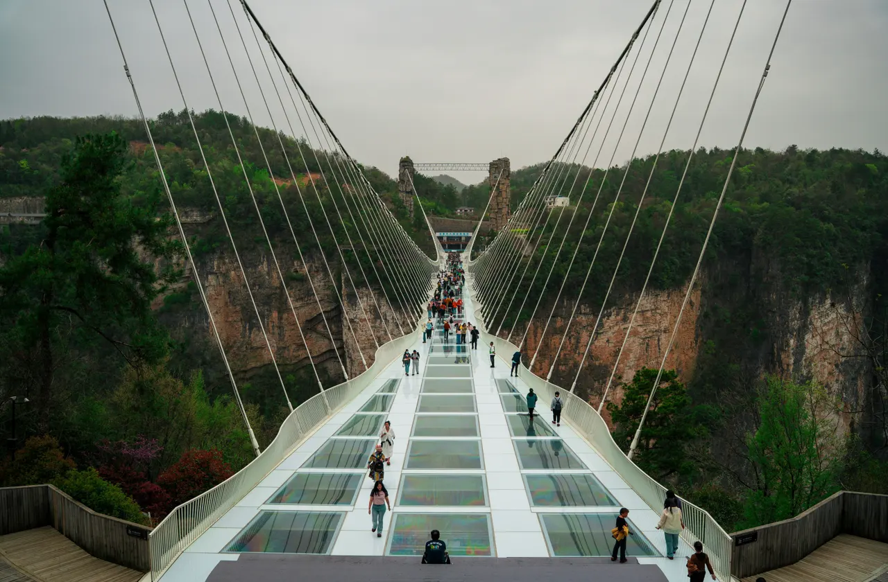People walk across a glass bridge