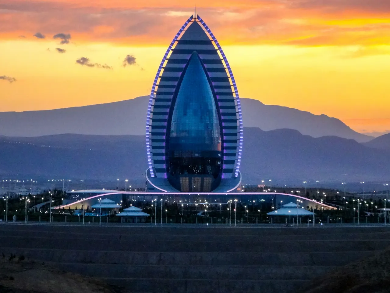 Modern building illuminated at sunset with mountains background