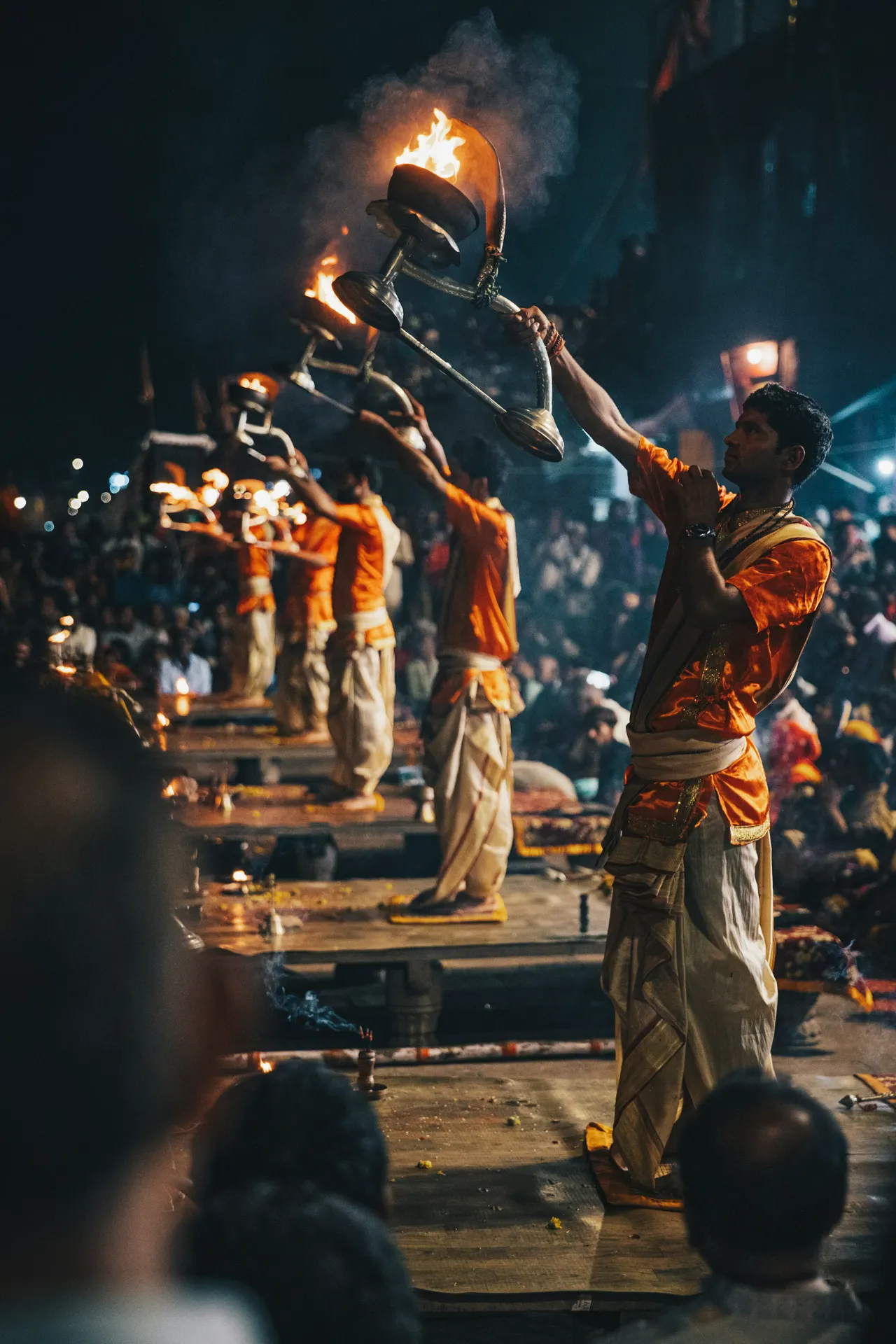 Men in orange robes performing a fire ritual with lamps in Varanasi, India