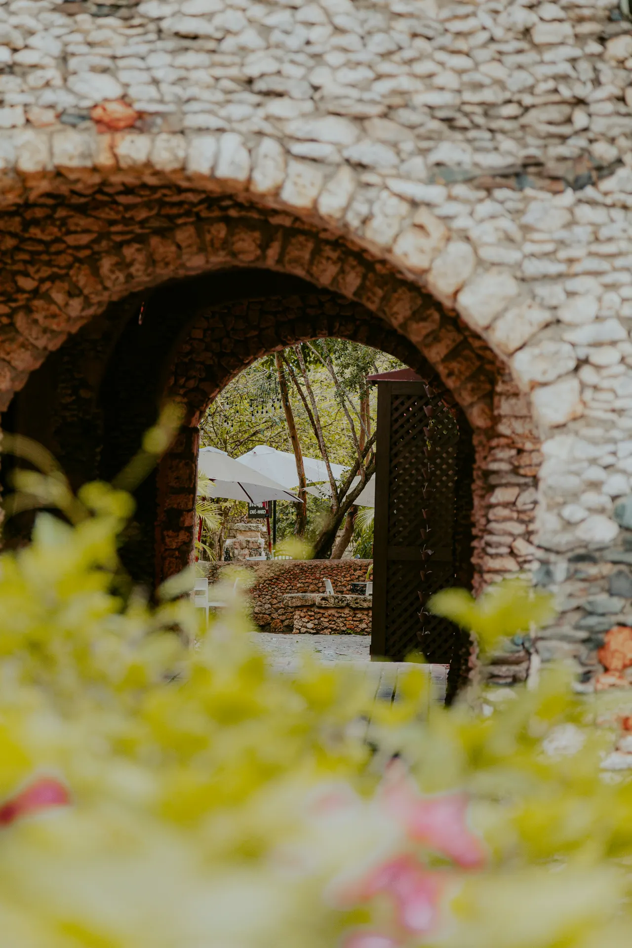 A bride and groom walking through a stone archway