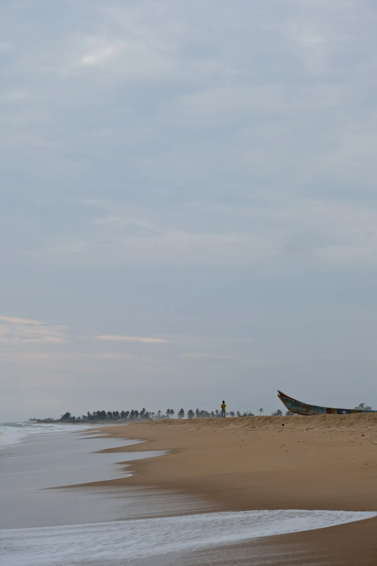 A boy and a fishing boat on Fidjrosse beach, Cotonou, Benin, October 2024