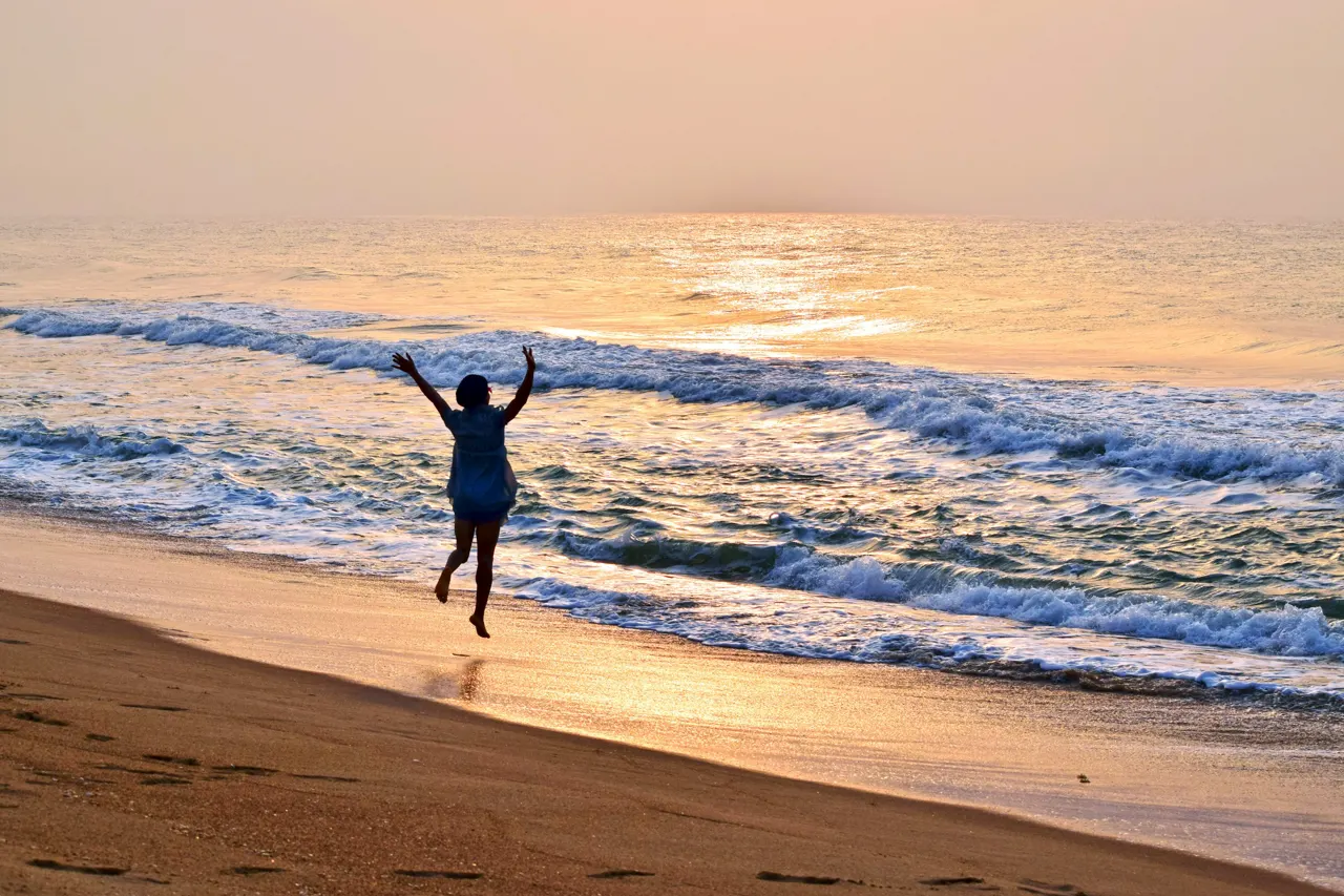 A person running on the beach with their arms in the air