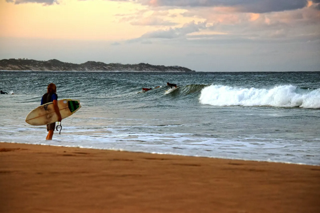 A person walking on a beach with a surfboard