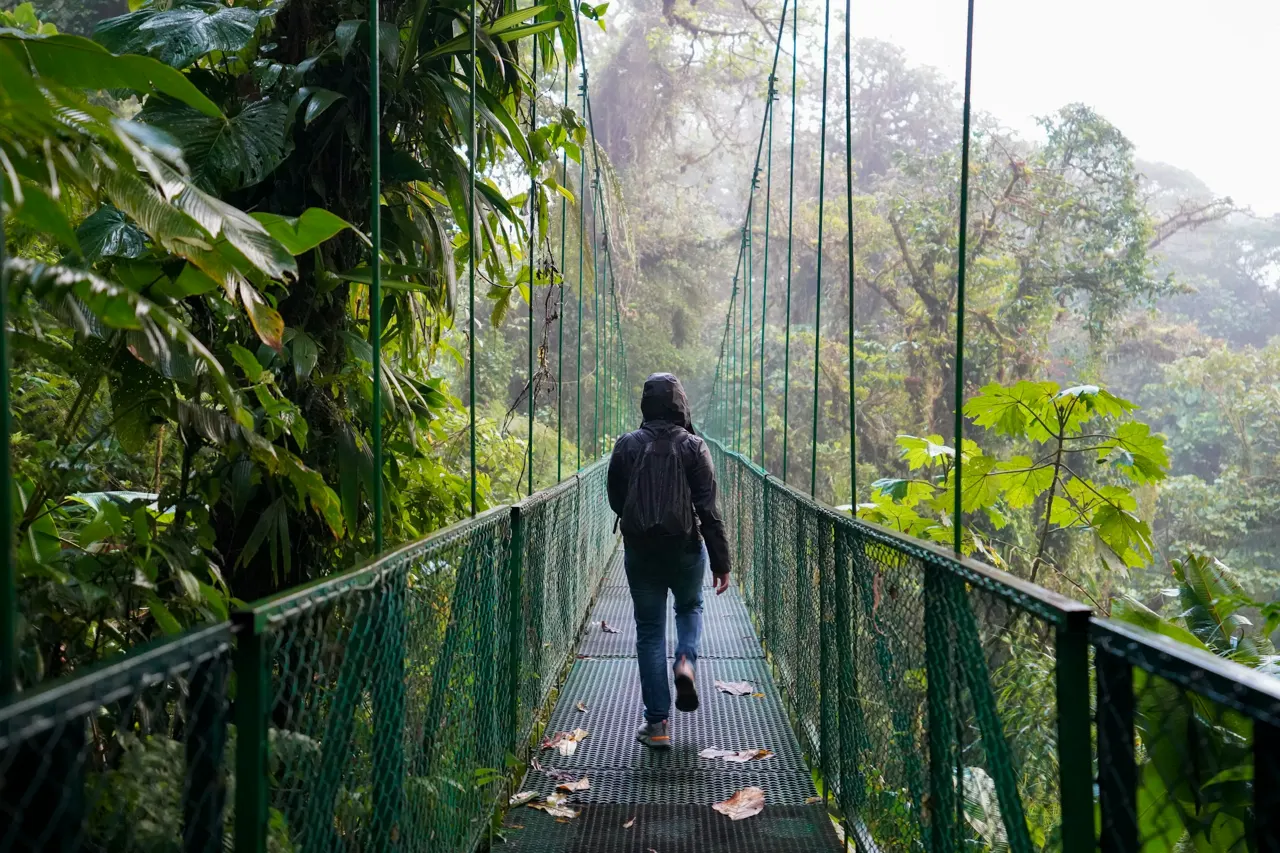 Guy crossing a hanging bridge within the Cloud Forest in La Fortuna, Costa Rica