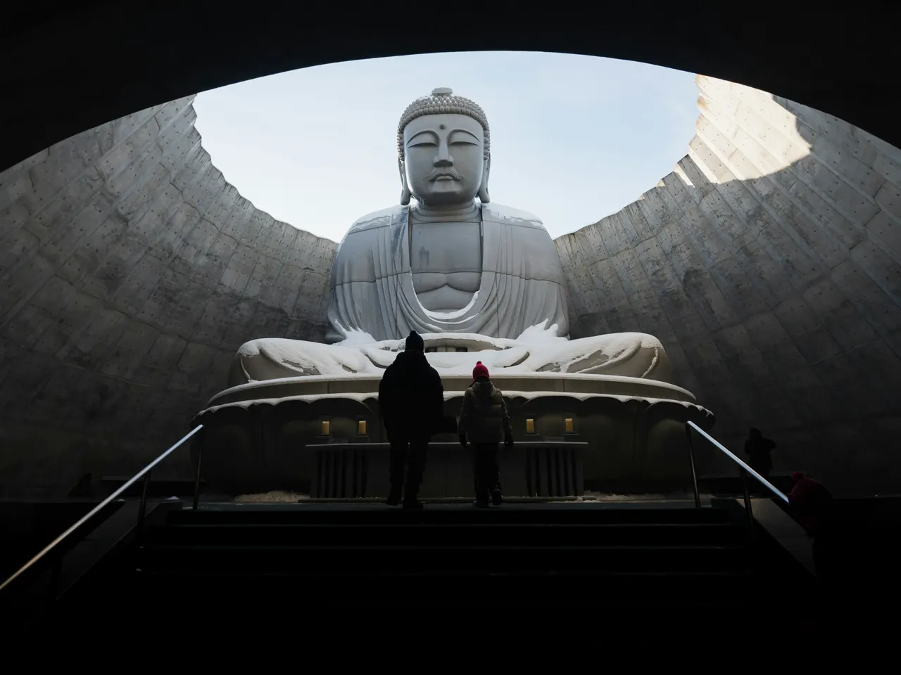 A person standing in front of a large buddha statue