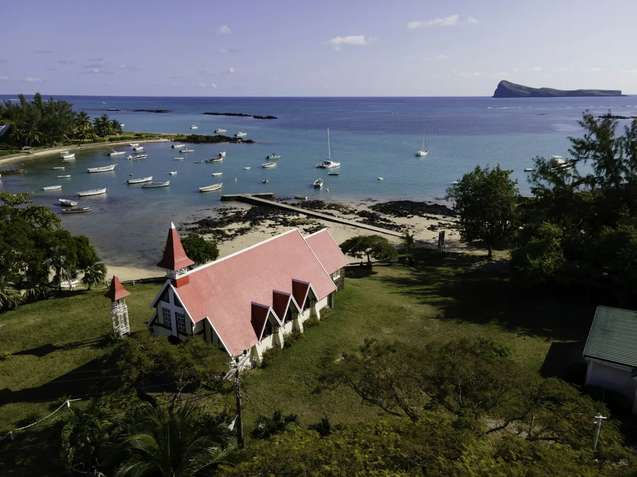 an aerial view of a small church on the shore