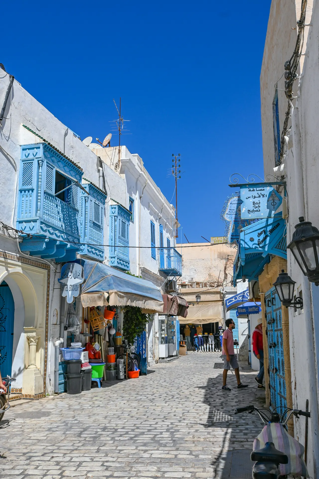 Cobblestone street lined with shops and blue balconies