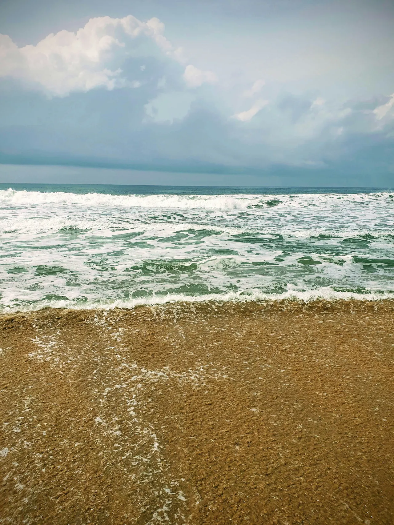 a sandy beach with waves coming in to shore