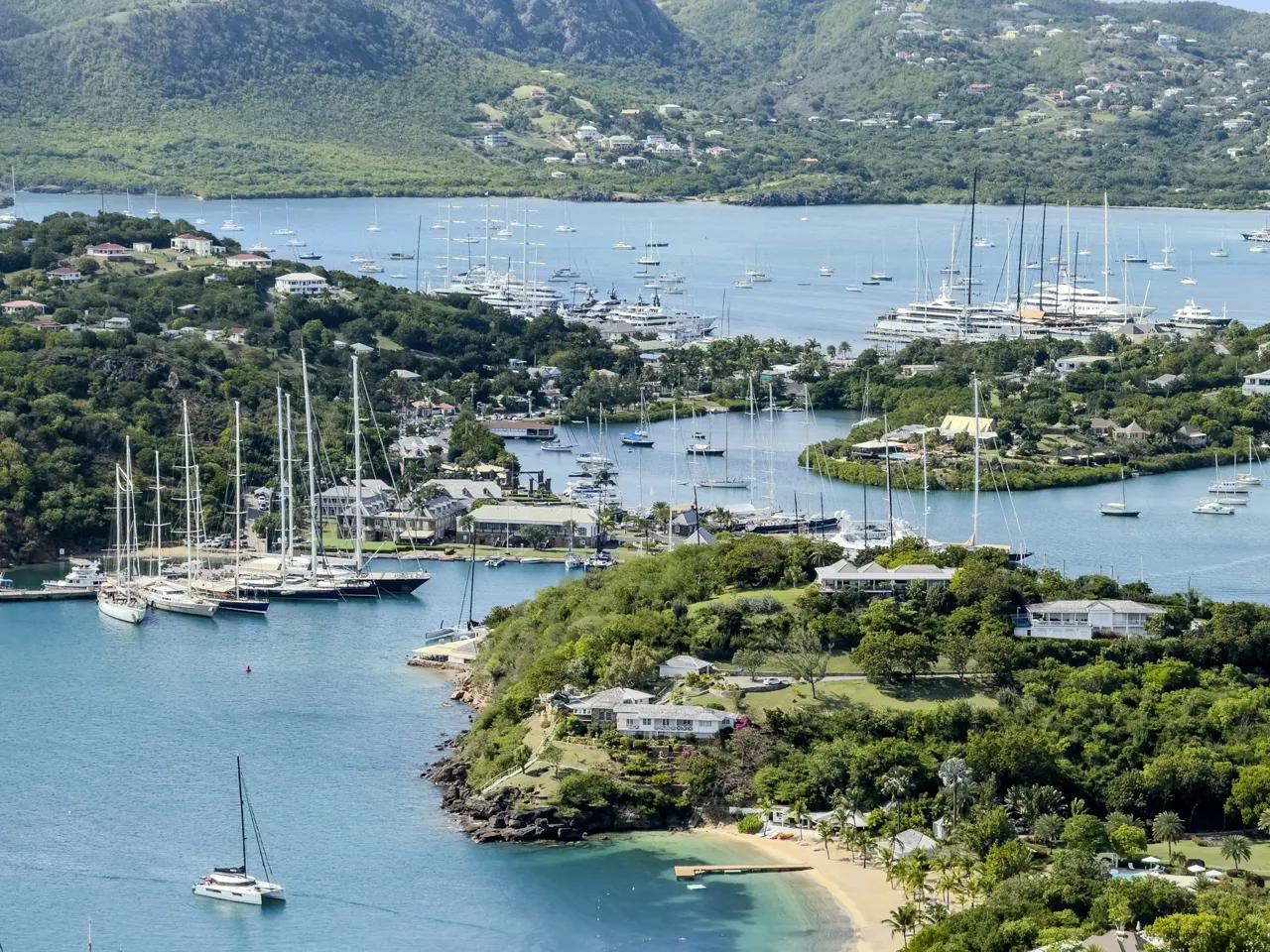 Sailing yachts anchored in a tropical bay with green hills
