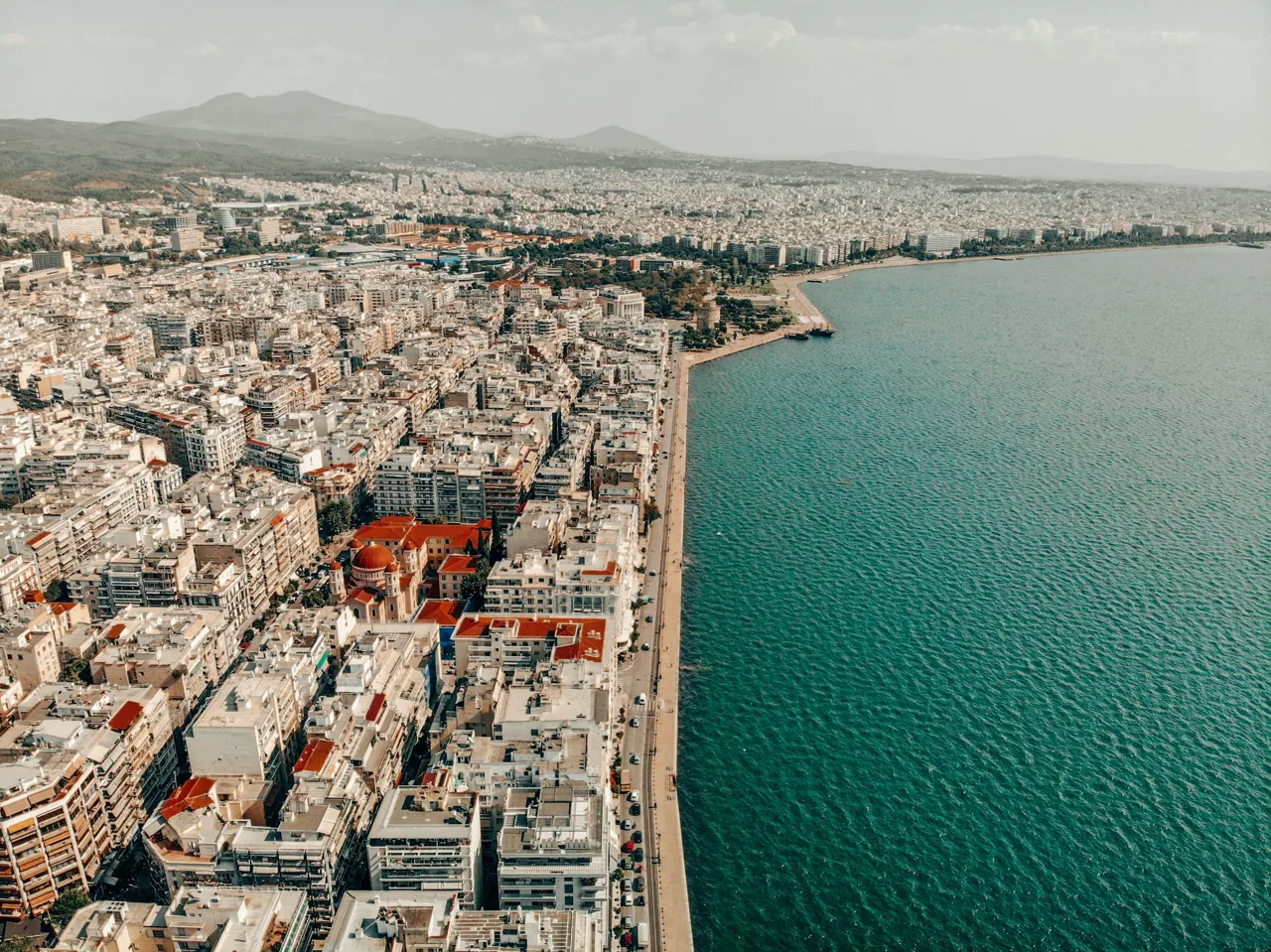 an aerial view of a city next to a body of water